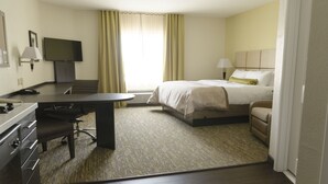 A hotel room with a bed, a desk, a chair, a television, and a window with curtains.