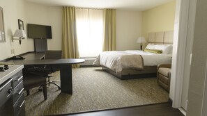 Ein Hotelzimmer mit Bett, Schreibtisch, Stuhl, Fernseher und einem Fenster mit Vorhängen.