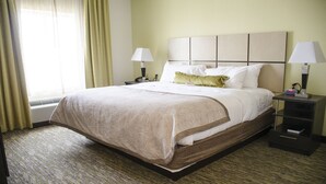 A hotel room with a large bed, two bedside lamps, a nightstand, and a window with curtains.