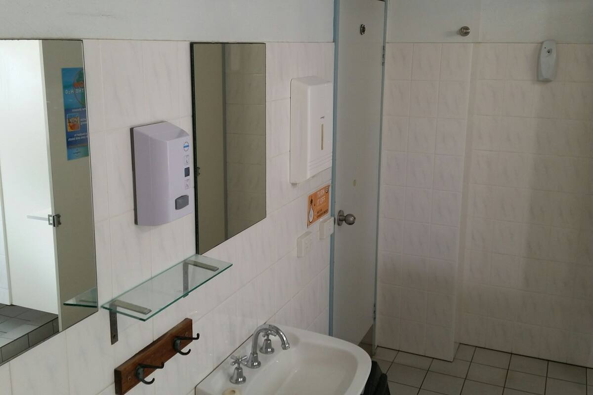 A bathroom with a glass shelf, a sink, a mirror, and a door.