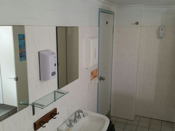 A bathroom with a glass shelf, a sink, a mirror, and a door.