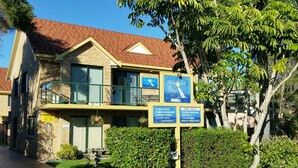 Un edificio de dos plantas con techo de tejas rojas, un balcón y un cartel anunciando 'Wandahl Lodge' en Merimbula.