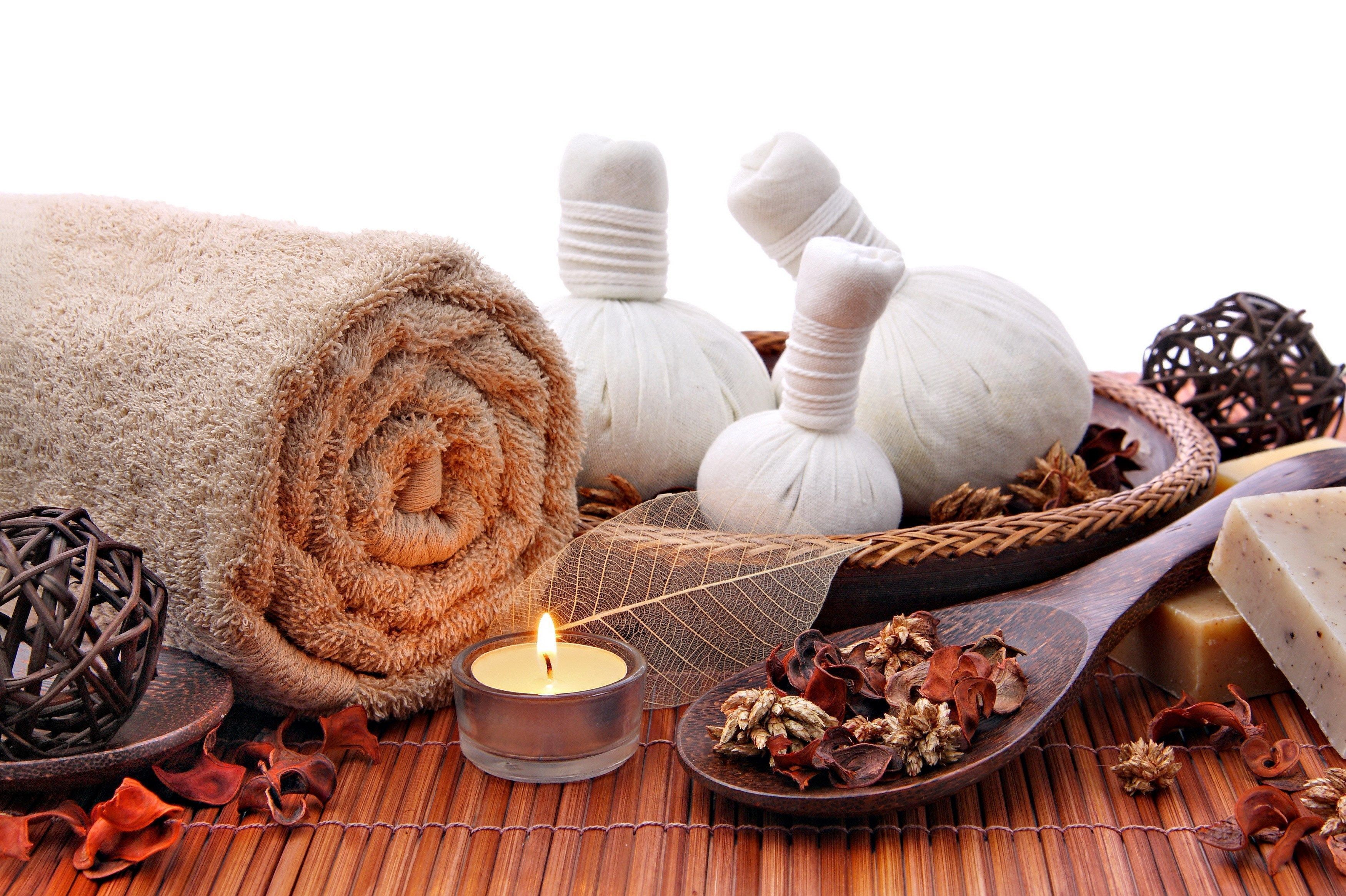 A spa setting with a rolled towel, candles, and massage stones.