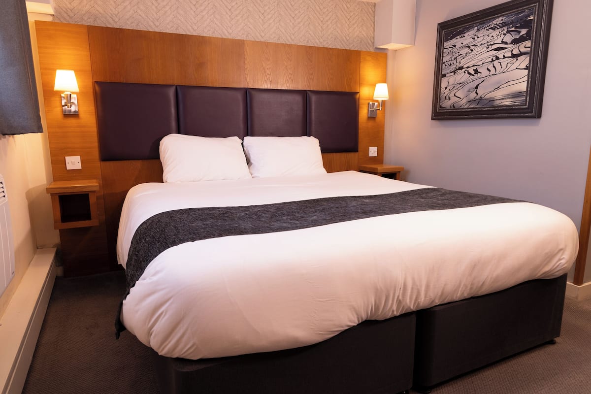 Una cama bien hecha con cabecera de madera y dos lámparas de noche.