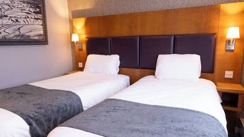 A hotel room with two beds, a wooden headboard, bedside lamps, and a framed picture on the wall.