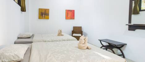 Habitación de hotel con dos camas, una mesita y dos sillas. Hay dos cuadros en la pared.