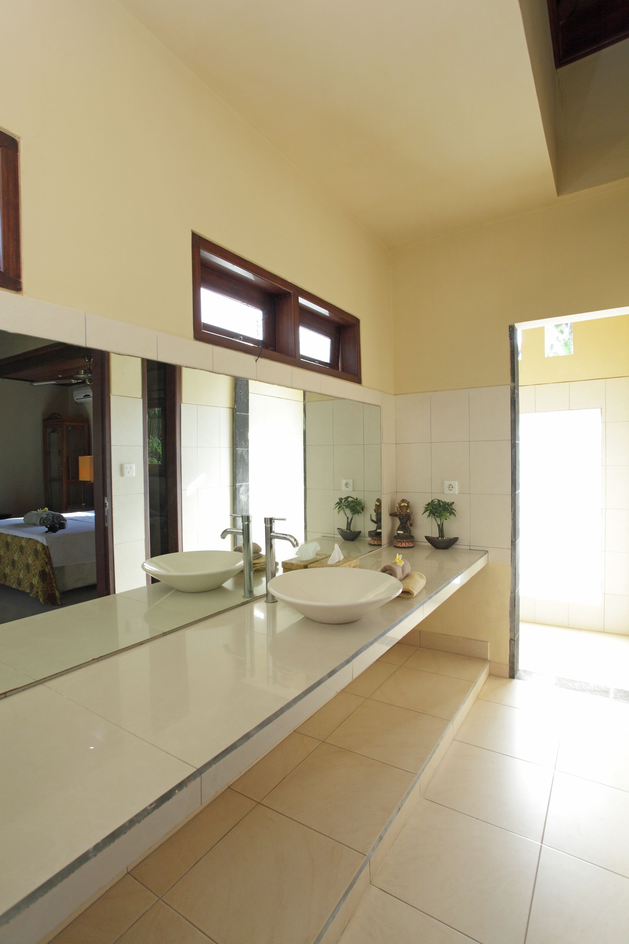A modern bathroom with a large mirror, two sinks, and a toilet.