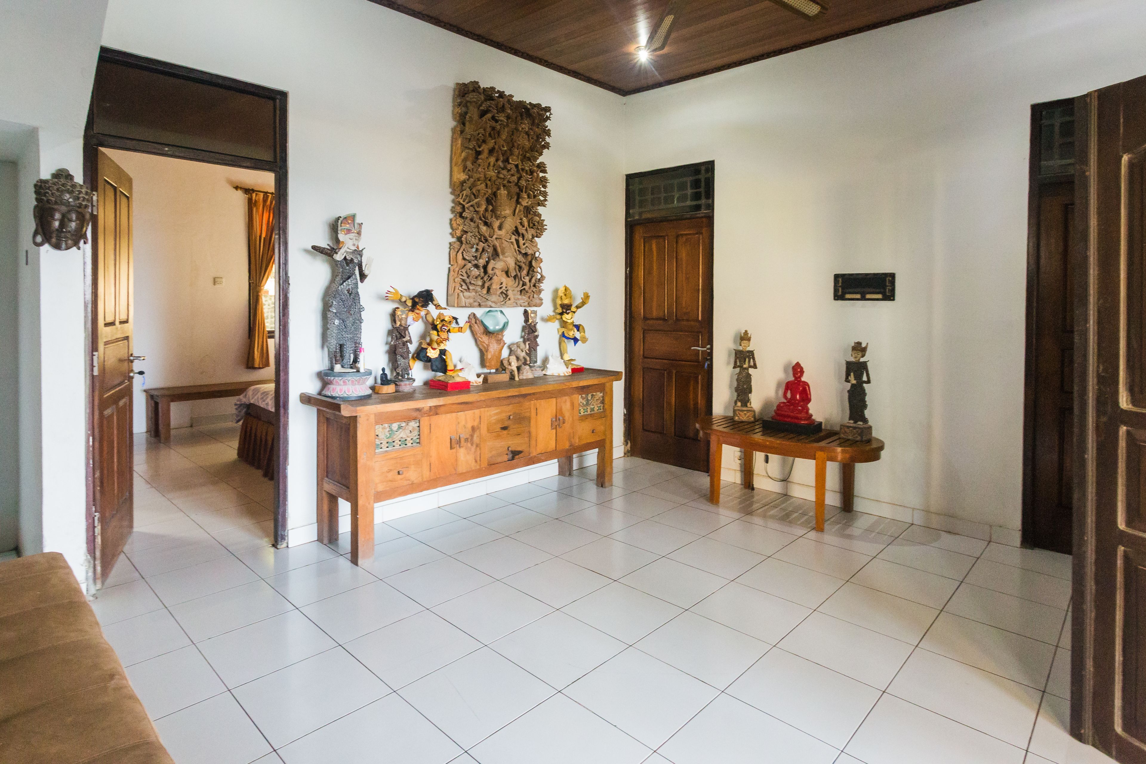 A spacious room with a wooden cabinet displaying various statues and a large carved wooden panel on the wall.