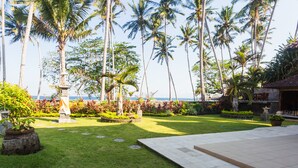 Ein gepflegter Garten mit Palmen, einem Kiesweg und Blick auf das Meer.