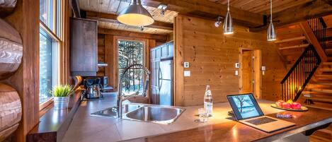 L’intérieur d’une cabane en bois, avec un comptoir de cuisine, un ordinateur portable et une bouteille d’eau.