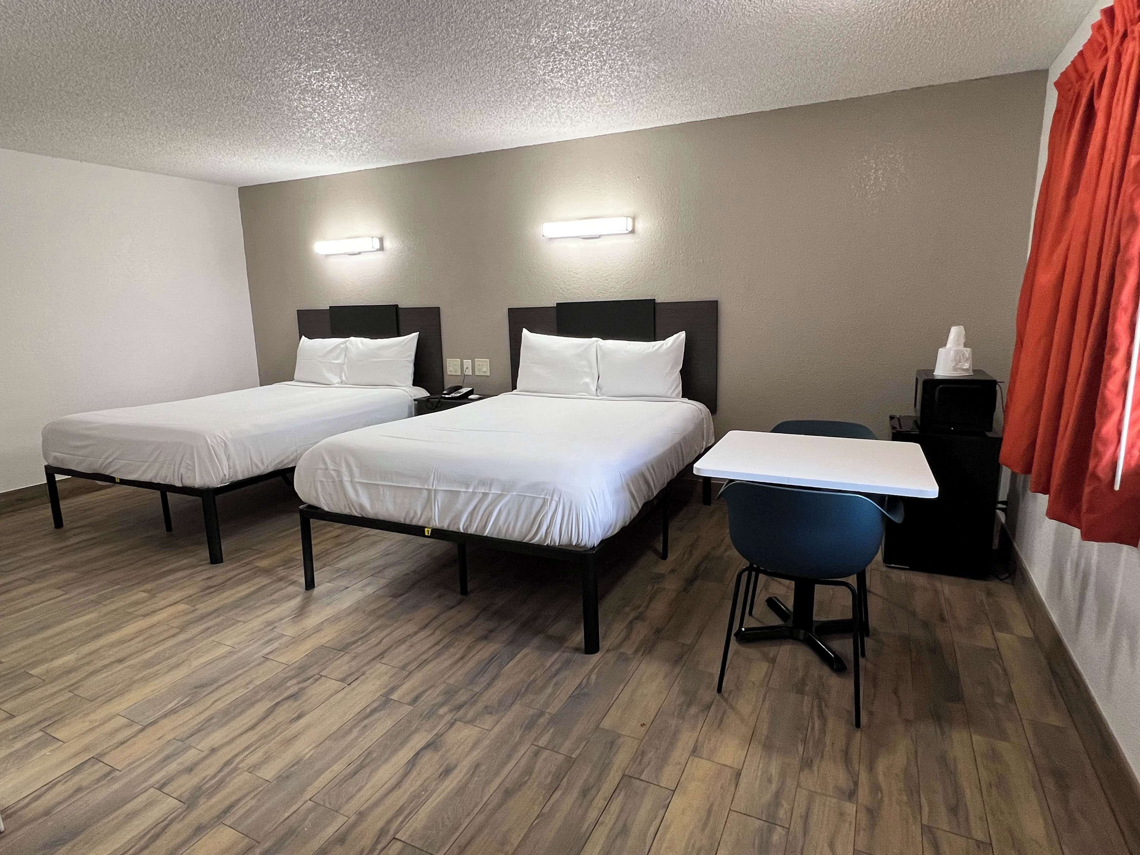 Una habitación de hotel con dos camas individuales, un escritorio y una silla.