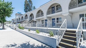 A hotel with multiple balconies, a concrete facade, and a staircase leading to the entrance. - Motel 6 Orange, CA - Anaheim (Orange)