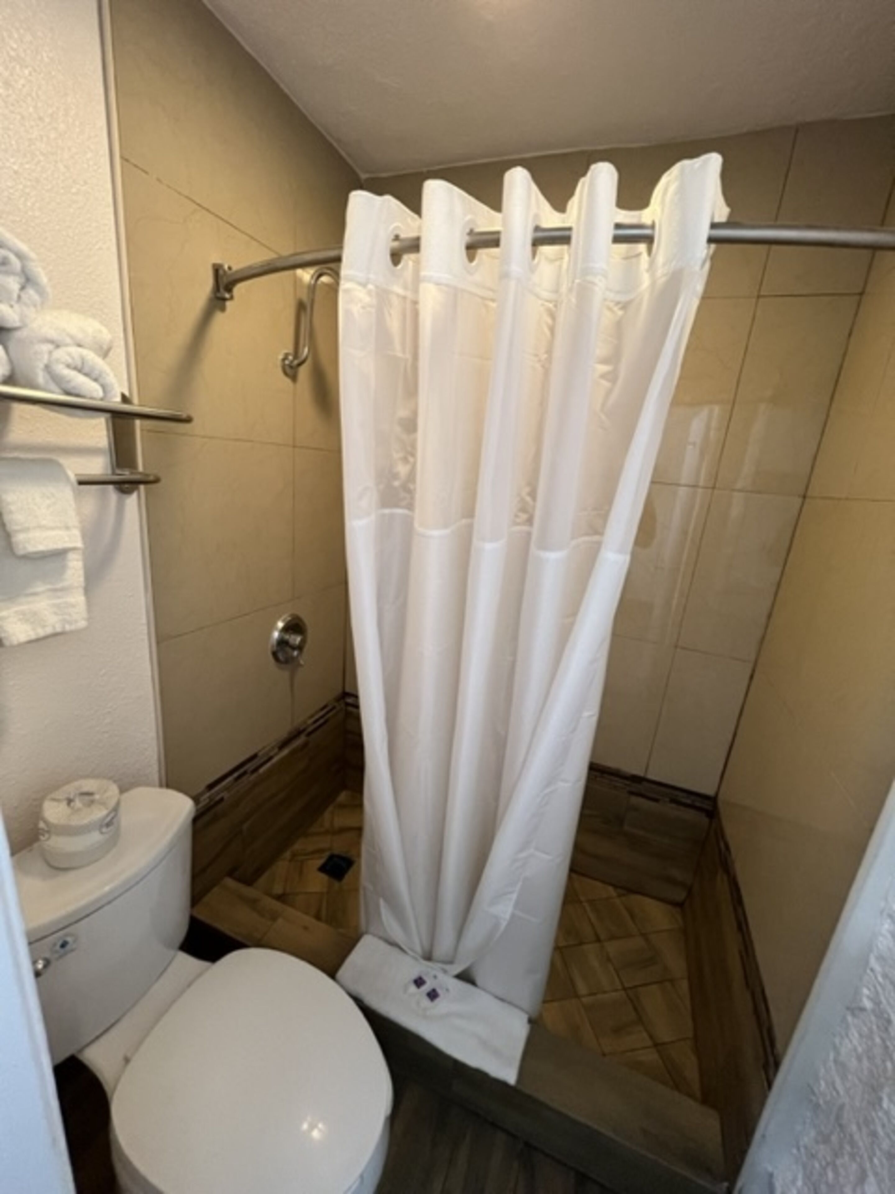 Um banheiro pequeno com cortina de chuveiro, vaso sanitário e porta-toalhas com toalhas.