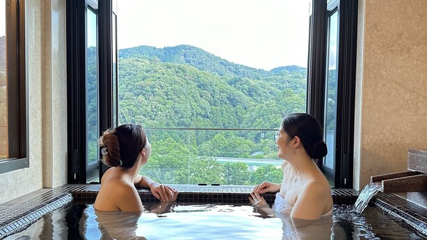 Two people in a hot tub with a view of a forested mountain. - Condominium Hotel Garland Court Usami (Ito)