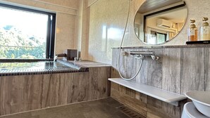 A modern bathroom with a large window, a built-in sink, a shower, and a vanity with a mirror. - Condominium Hotel Garland Court Usami (Ito)