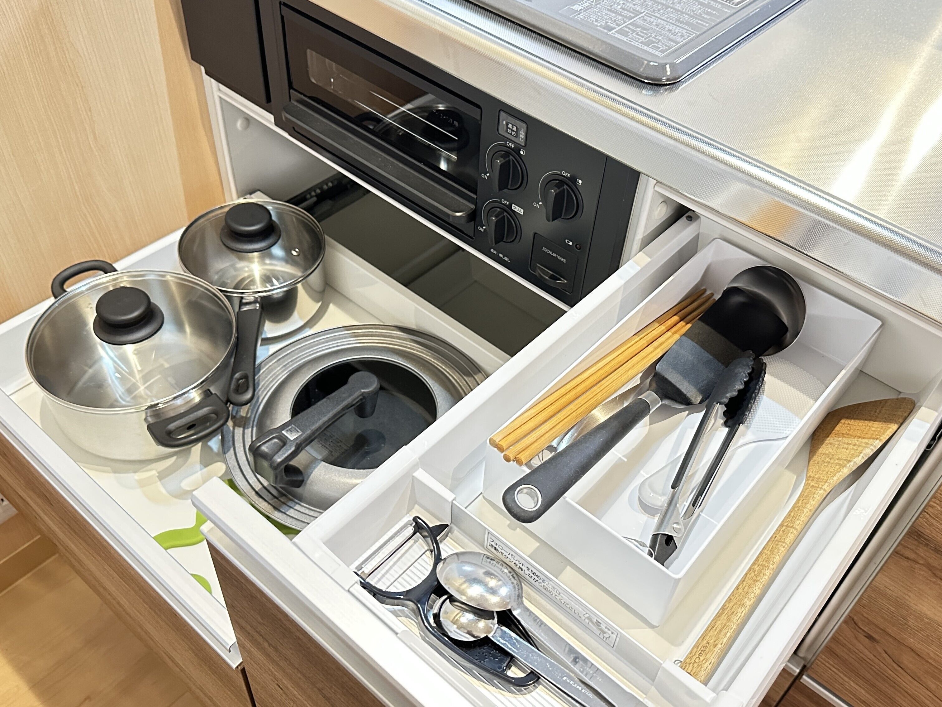Una cocina con estufa, ollas, tetera y utensilios.
