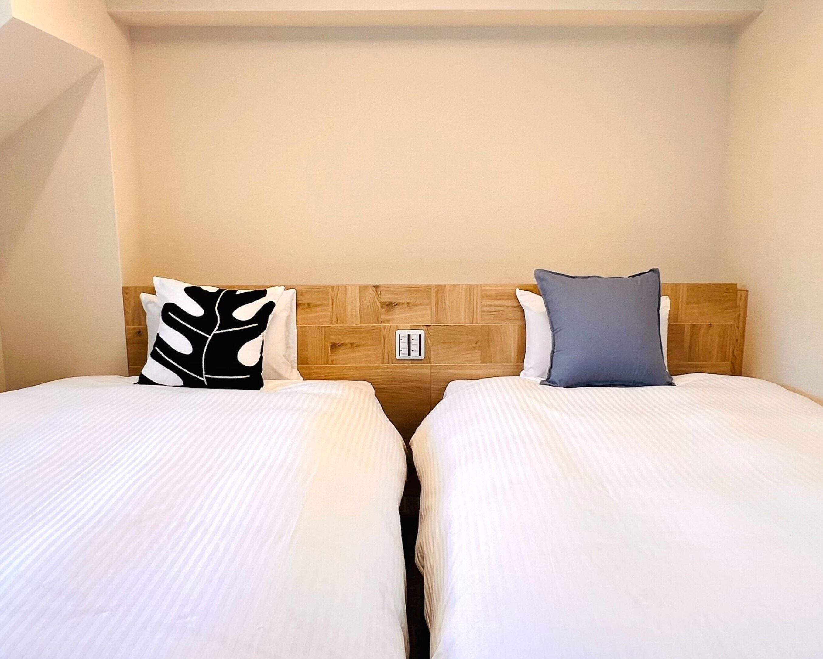 A hotel room with two single beds, each with a pillow and a wooden headboard.