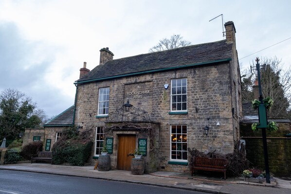 A stone building with a sign reading "ROCKINGHAM ARMS."