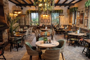 A cozy restaurant with wooden tables and chairs, hanging plants, and framed pictures on the walls. - Rockingham Arms by Greene King Inns (Rotherham)