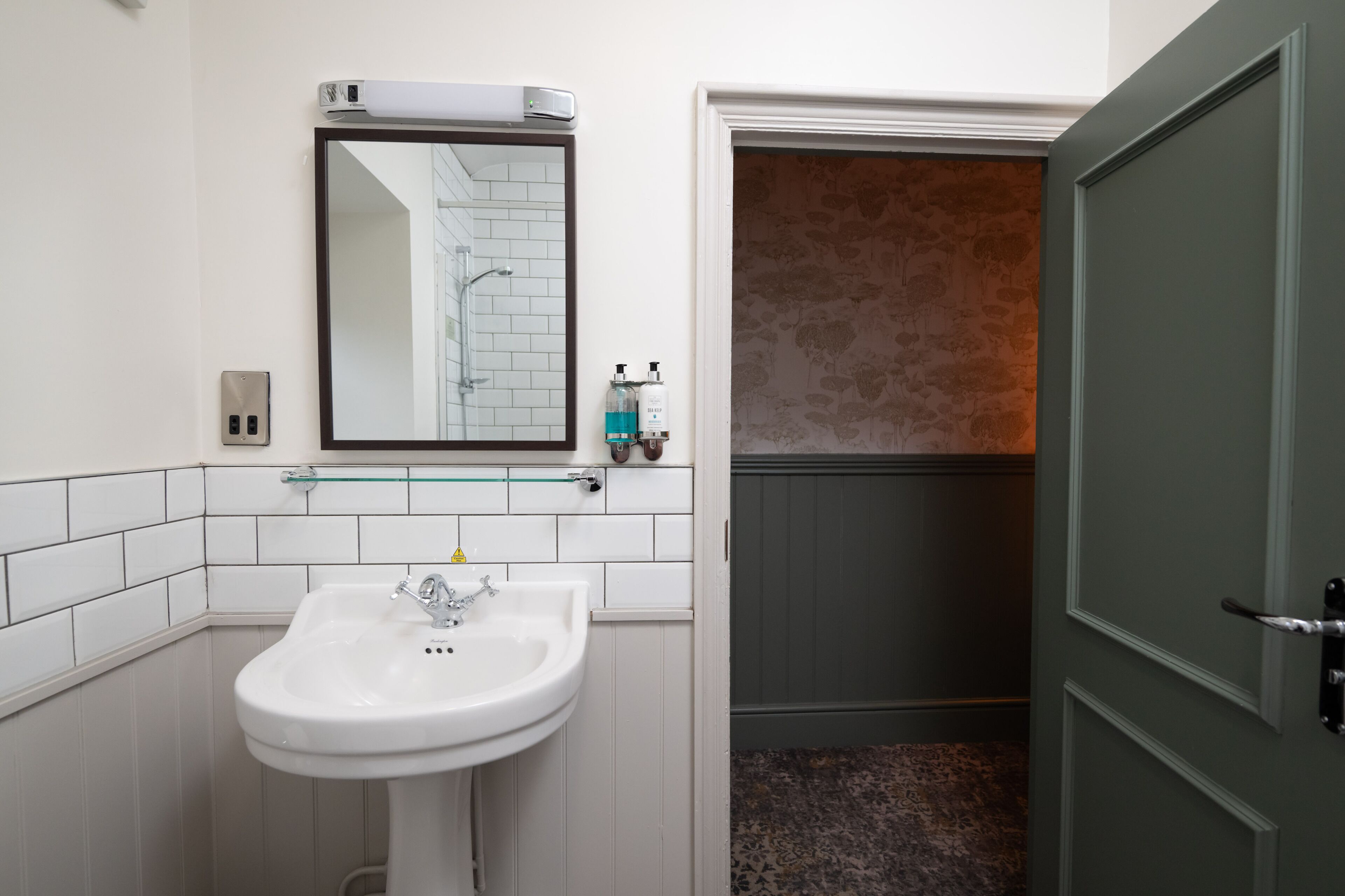 A bathroom with a white sink, a mirror, and a towel rack.