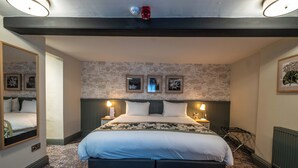 Une chambre d’hôtel moderne avec un grand lit, deux lampes de chevet, un miroir et un radiateur.