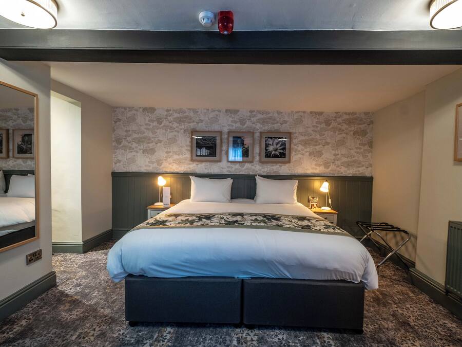 A modern hotel room with a large bed, two bedside lamps, a mirror, and a radiator.