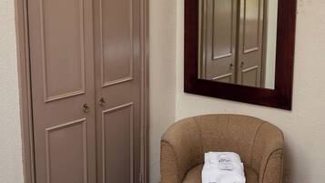 A hotel room with a double door, a chair with a towel, and a bed.
