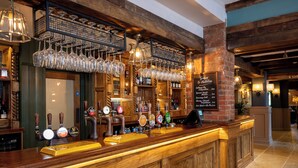 A bar area with multiple beer taps, a selection of glasses, and a menu board.