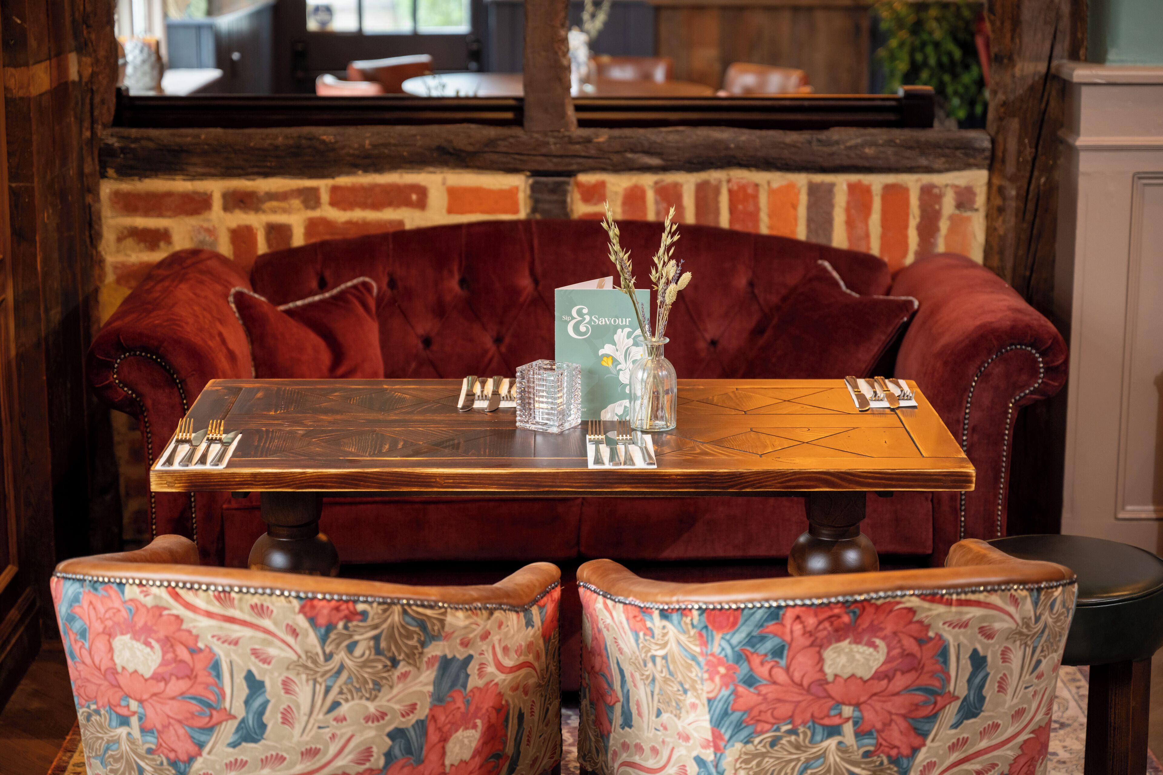 A dining table with a floral chair design, a vase with flowers, and a menu.