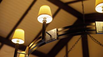 Un lustre doté de plusieurs abat-jours dans une pièce au plafond haut et aux poutres apparentes.