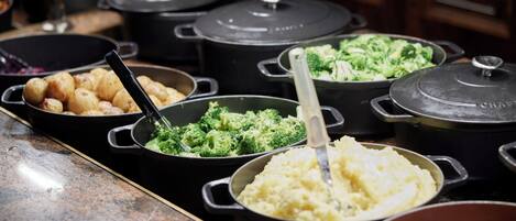 A buffet with various dishes including potatoes, broccoli, and carrots.