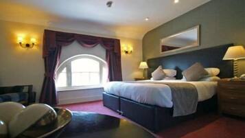 A hotel room with a large bed, bedside lamps, a mirror, and a view of the outdoors.