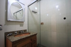 A bathroom with a granite countertop sink, a mirror, and a glass shower enclosure. - Ribeiro 704 (Rio de Janeiro)