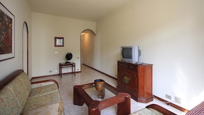 A living room with a sofa, a coffee table, a television on a wooden cabinet, and a framed picture on the wall. - Ribeiro 704 (Rio de Janeiro)