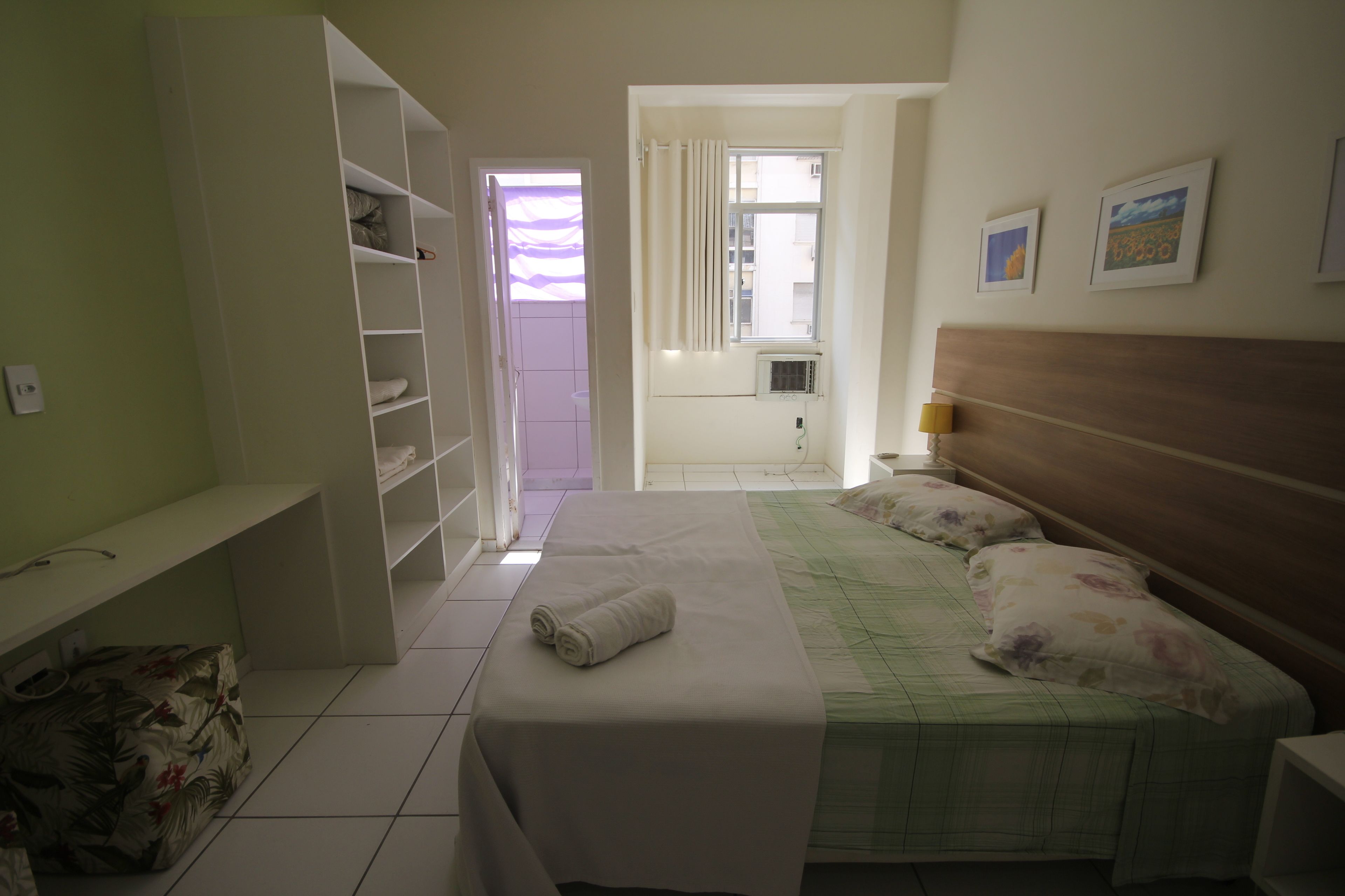 A hotel room with a bed, a desk, a wardrobe, and a window.
