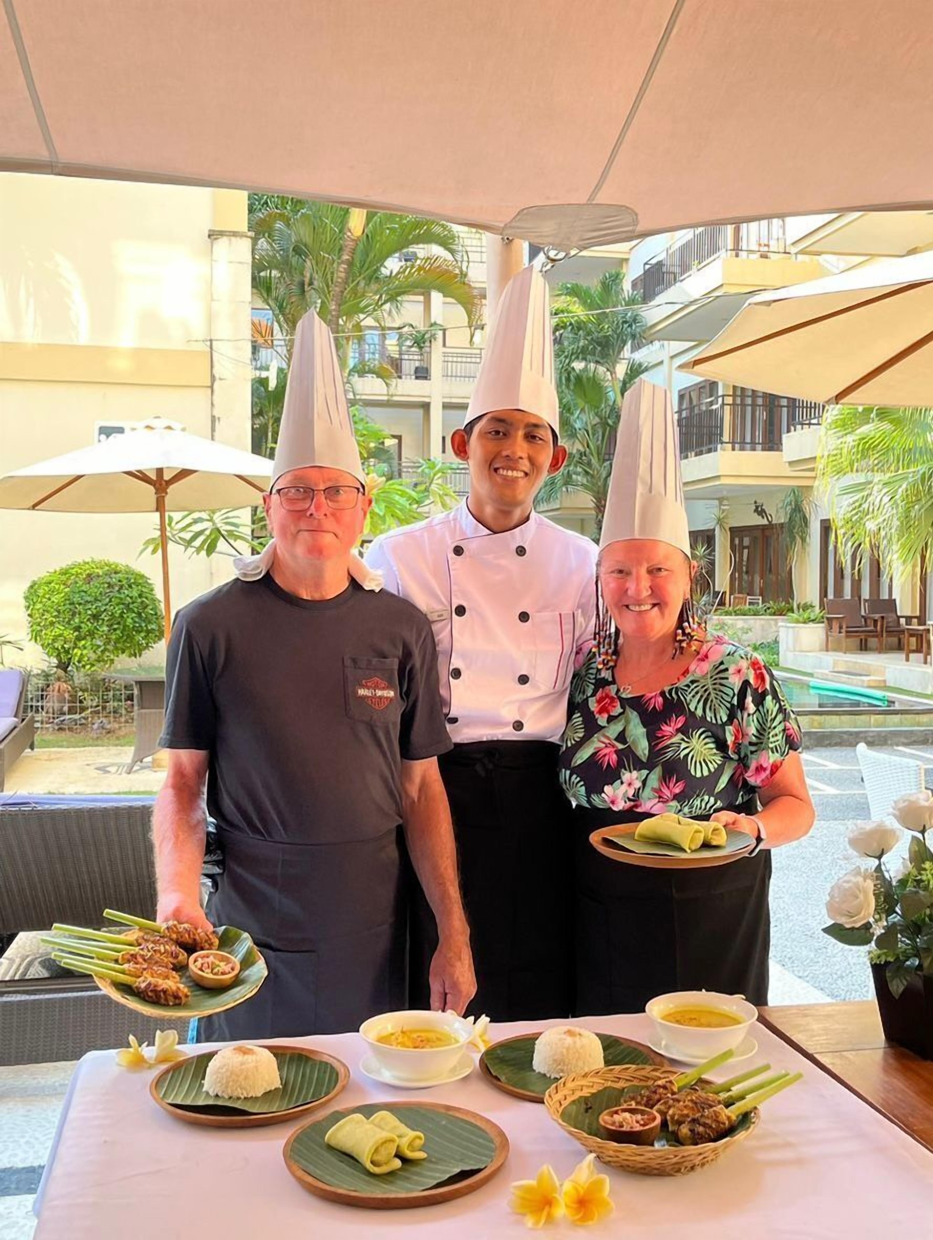 Three people in chef hats standing in front of a table with various dishes.