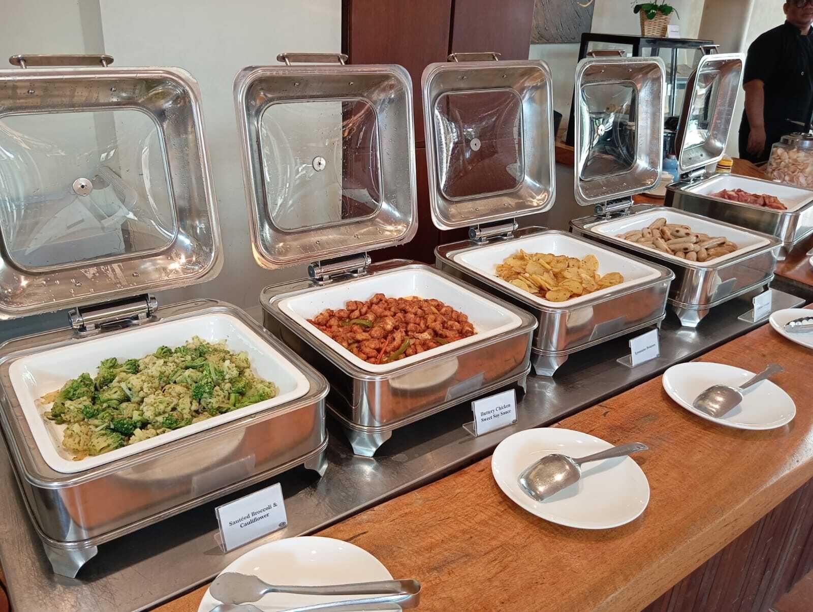A buffet with labeled containers of various foods including broccoli, beans, and sweet soy sauce.