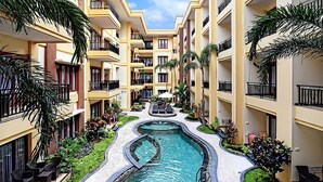 A multi-story hotel with a central swimming pool, balconies, and outdoor seating areas. - Kuta Townhouse Apartments (Kuta)
