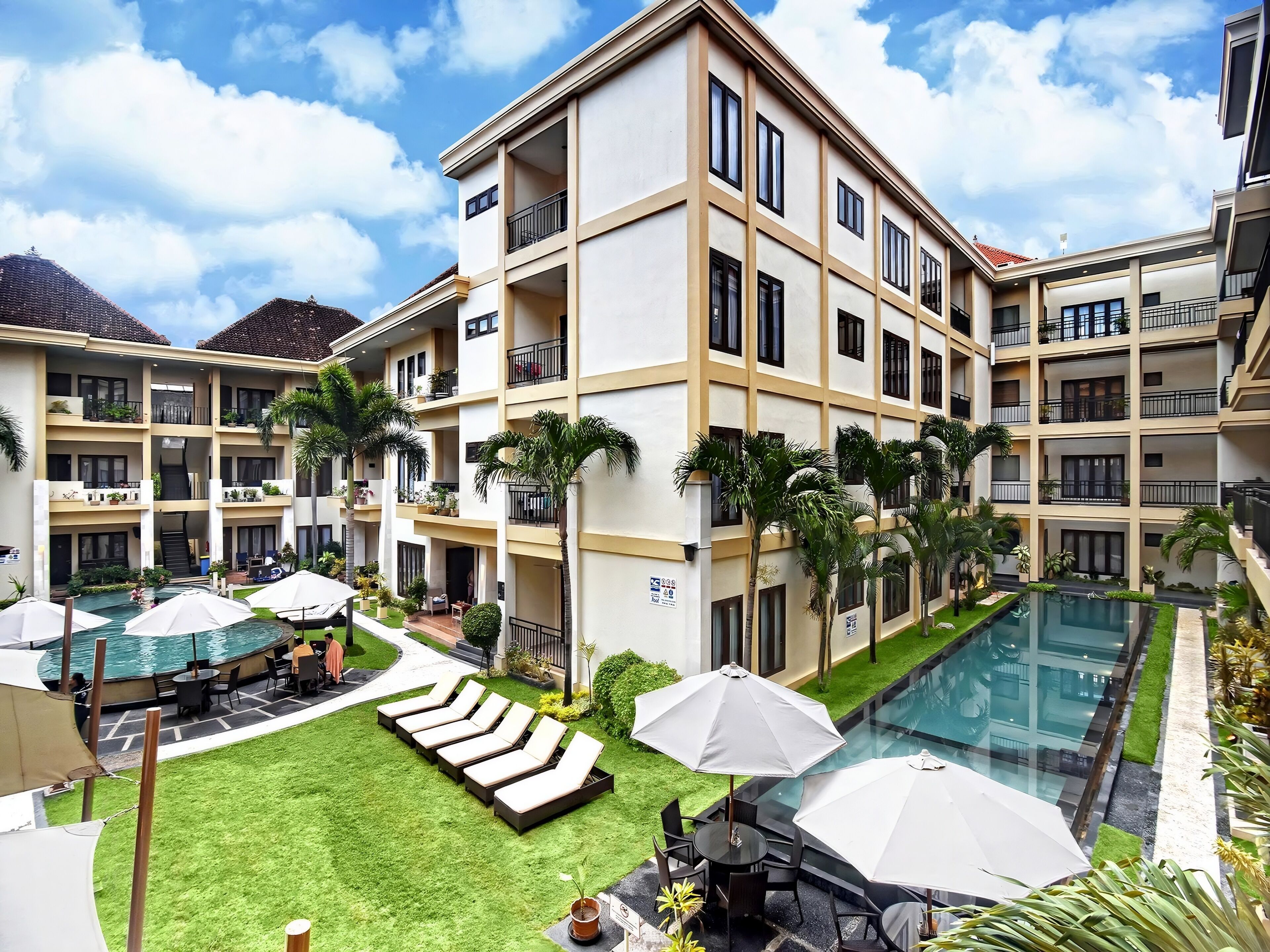 A multi-story hotel with balconies, a swimming pool, and outdoor seating areas.