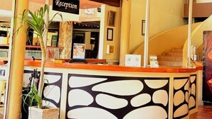 A reception desk with a sign, a ceiling fan, and a plant. - Kuta Townhouse Apartments (Kuta)