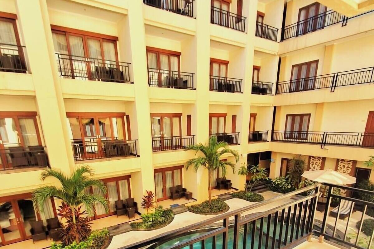 A multi-story hotel with balconies, outdoor seating, and a pool.