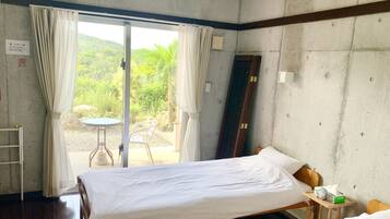 Habitación de hotel con una cama, una mesita con una caja de pañuelos y vistas al exterior.