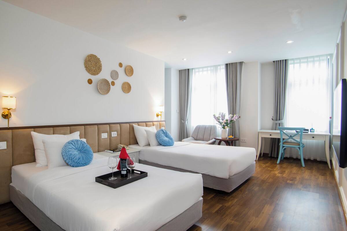 A hotel room with two beds, a desk, and a chair.