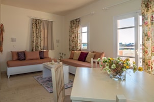 Una sala de estar acogedora con sofá, una mesita y una ventana con cortinas, con vistas al exterior.