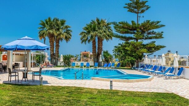 A pool area with lounge chairs, a bar, and a covered seating area. - Manolis Apartments (Hersonissos)