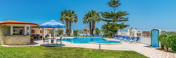 Zona de piscina con sillones reclinables, un bar y una zona de estar cubierta.