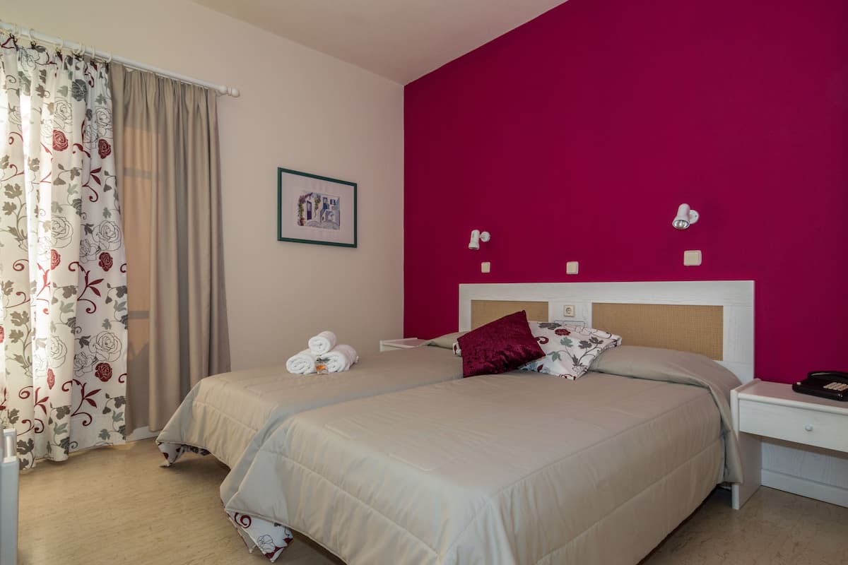 A double bed with a headboard, a bedside table with a lamp, and a wall-mounted picture.