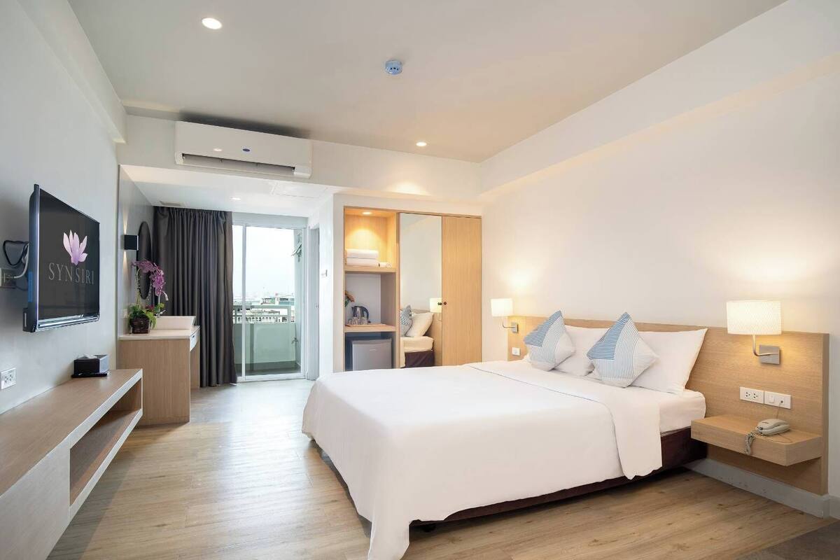 A hotel room with a bed, bedside tables, a TV, a desk, and a bathroom.