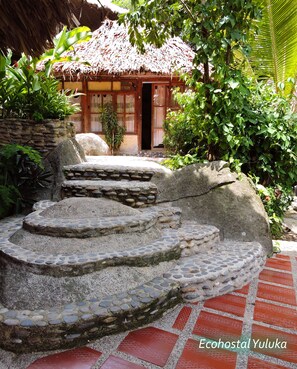 A traditional thatched-roof structure with a stone staircase leading to a wooden door. - Eco Hostal Yuluka (Santa Marta)