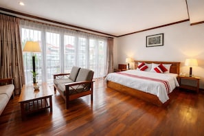 A hotel room with a bed, a wooden chair, a nightstand, a lamp, and a window with curtains. - Cheathata CTS Hotel Siem Reap (Siem Reap)